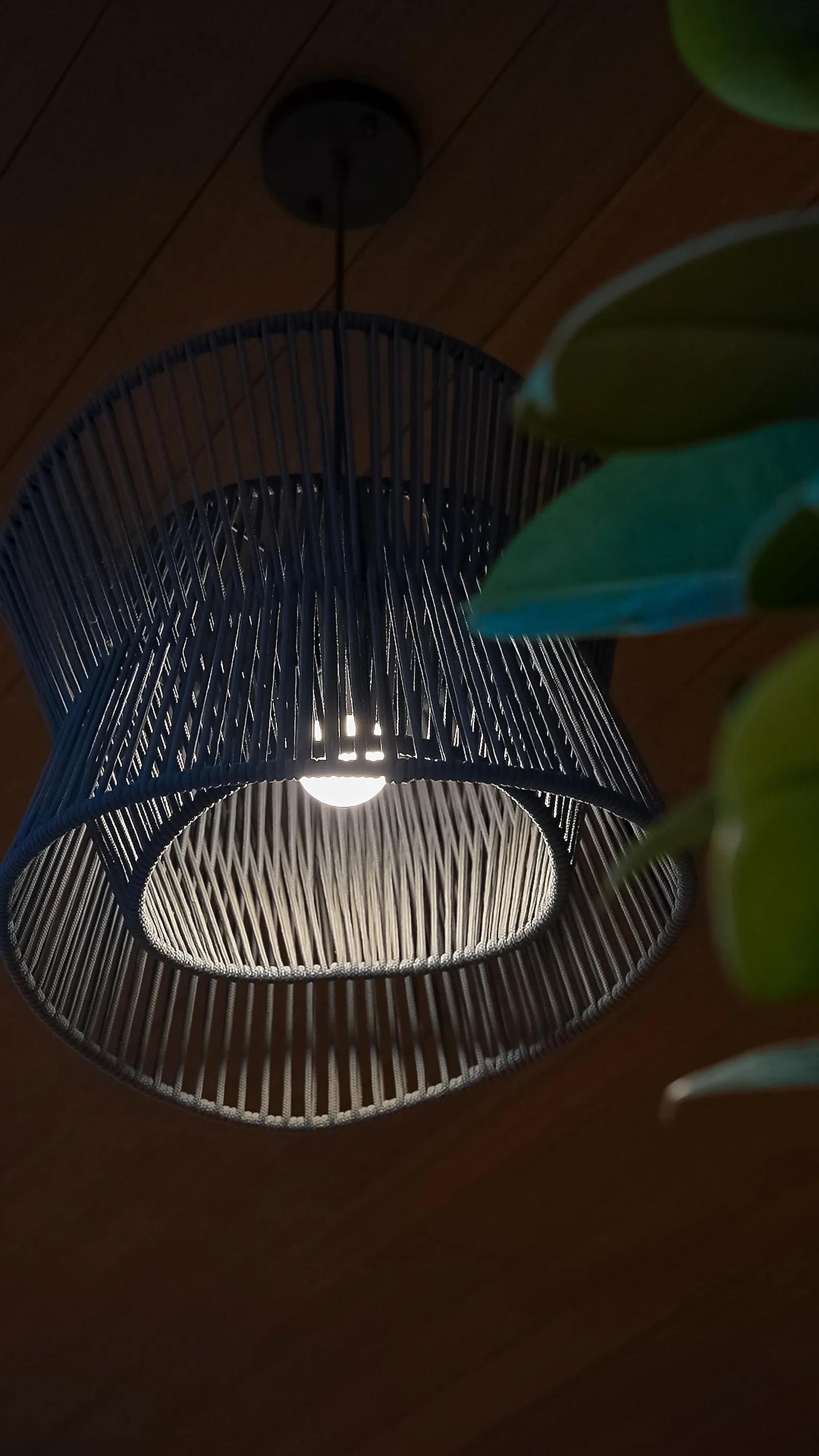 An open-weave pendant over the bar counter, its shade letting light through while shielding the lamp