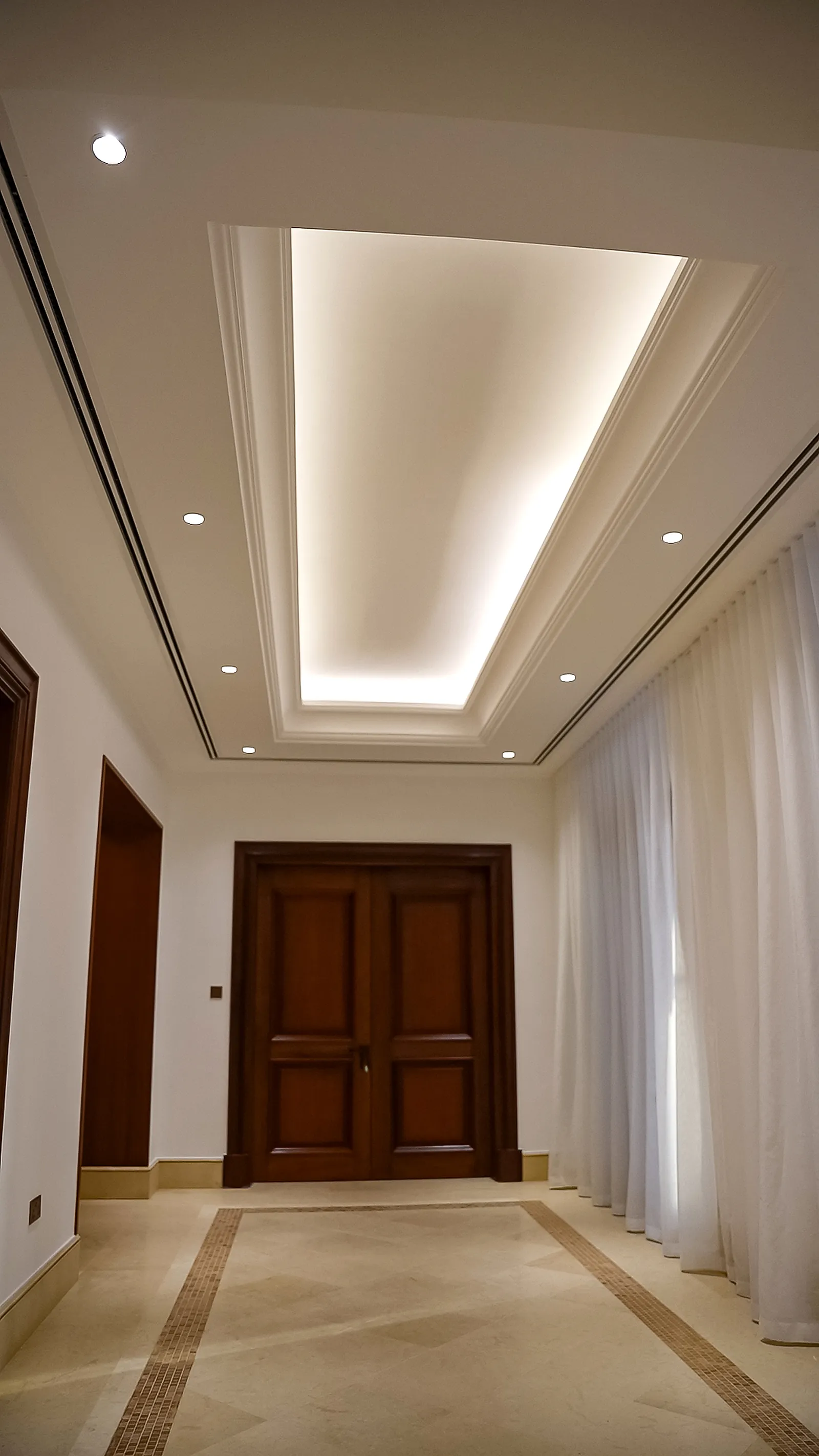 The villa corridor, lit by a cove concealed in a recessed ceiling tray with a few downlights in the flat