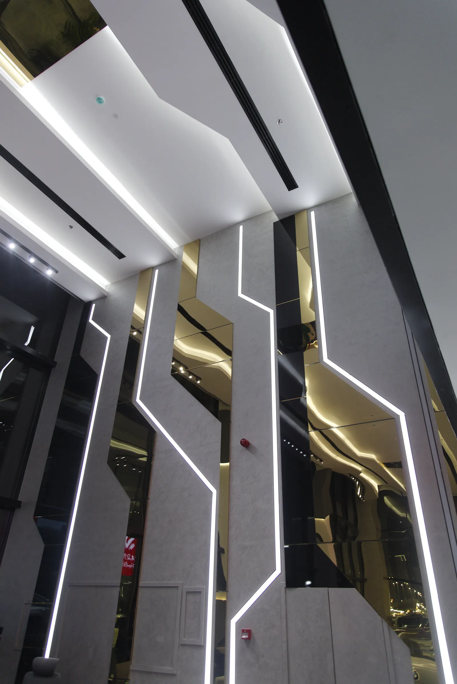 Angular linear profiles set flush into the wall panels at Al Weam, running between polished brass mirror strips