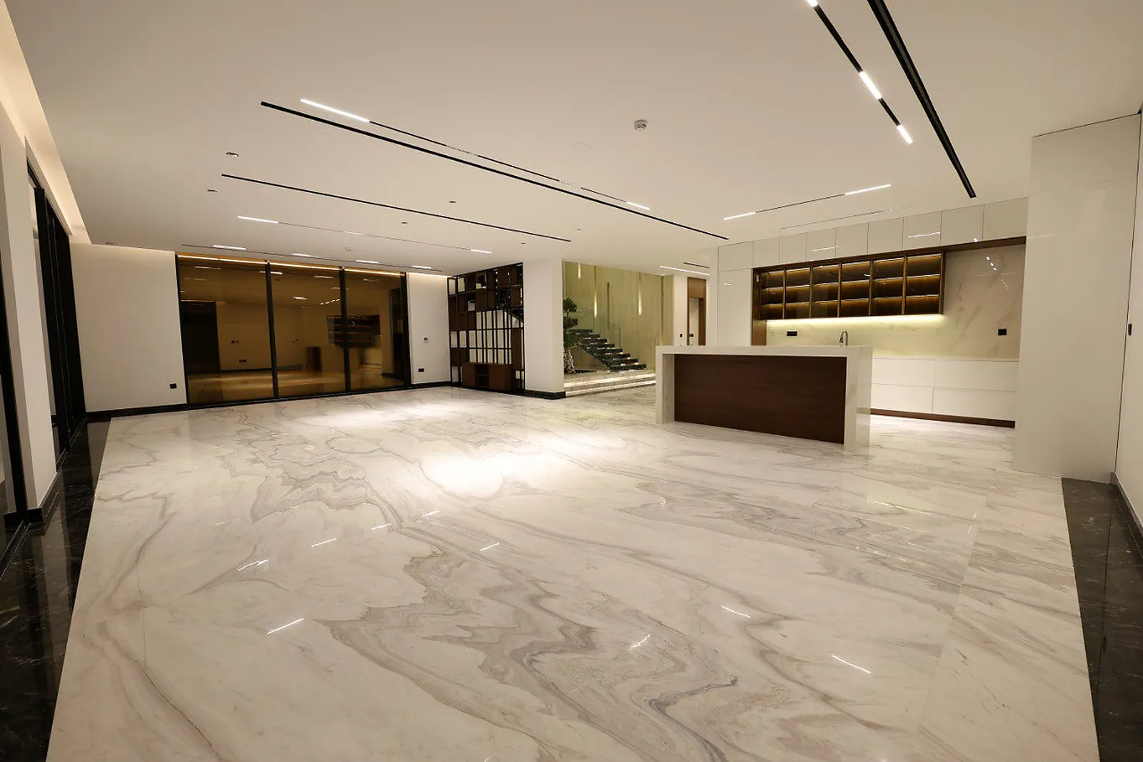 Black recessed ceiling channels carrying spaced linear modules in the open-plan living and kitchen space