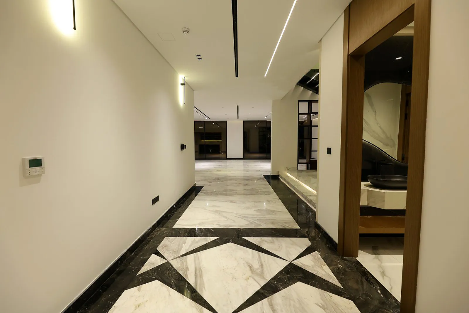 A ceiling channel, vertical wall fittings and a lit step nosing in the corridor of the Alkhafaji villa