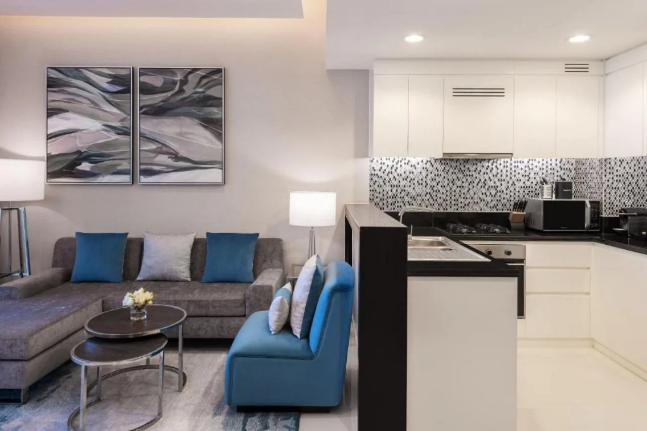 A serviced apartment at Aykon City with an open kitchen behind the living area, lit by recessed downlights