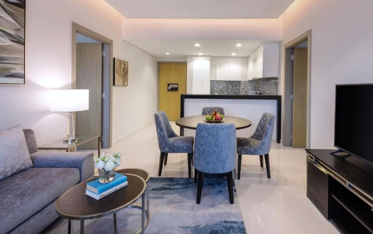 A serviced apartment living and dining room at Aykon City, lit by a perimeter cove and a short list of downlights