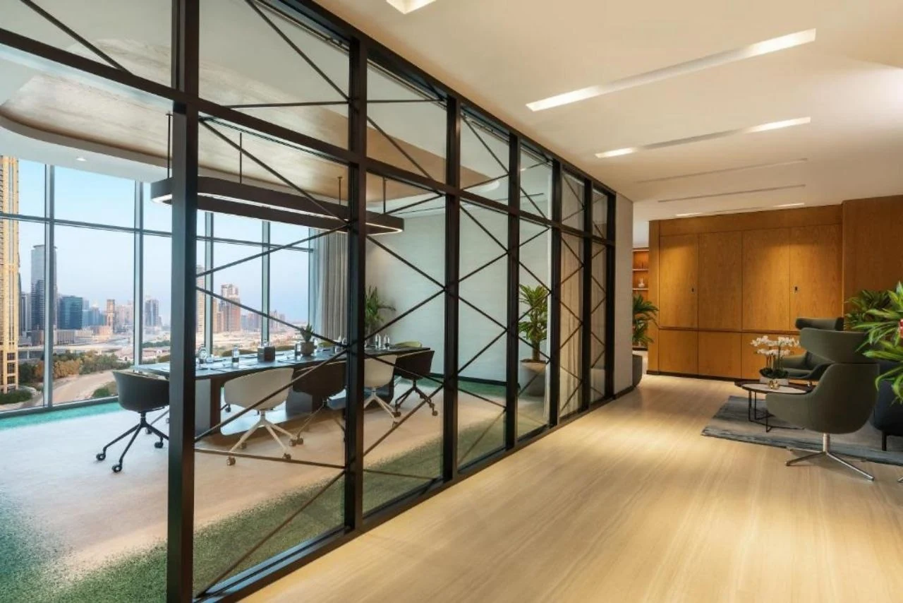 A glazed workspace at Aykon City with recessed linear runs in the plaster ceiling and a city view beyond
