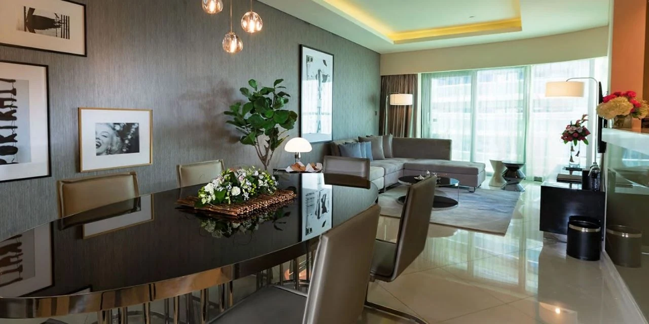 A dining table at Paramount Tower lit by a cluster of small pendants, with a lit cove beyond