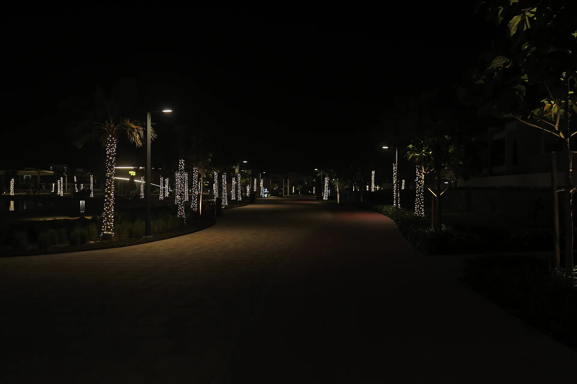 A lit walkway through a residential district in Dubai South at night