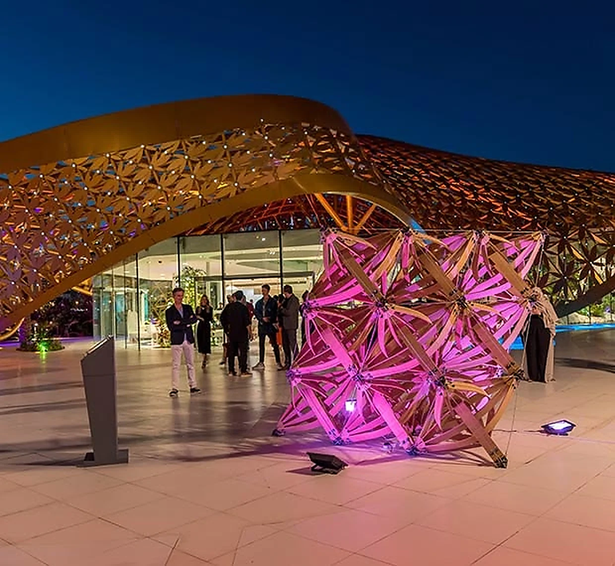 A timber lattice installation inside the pavilion, lit magenta from within