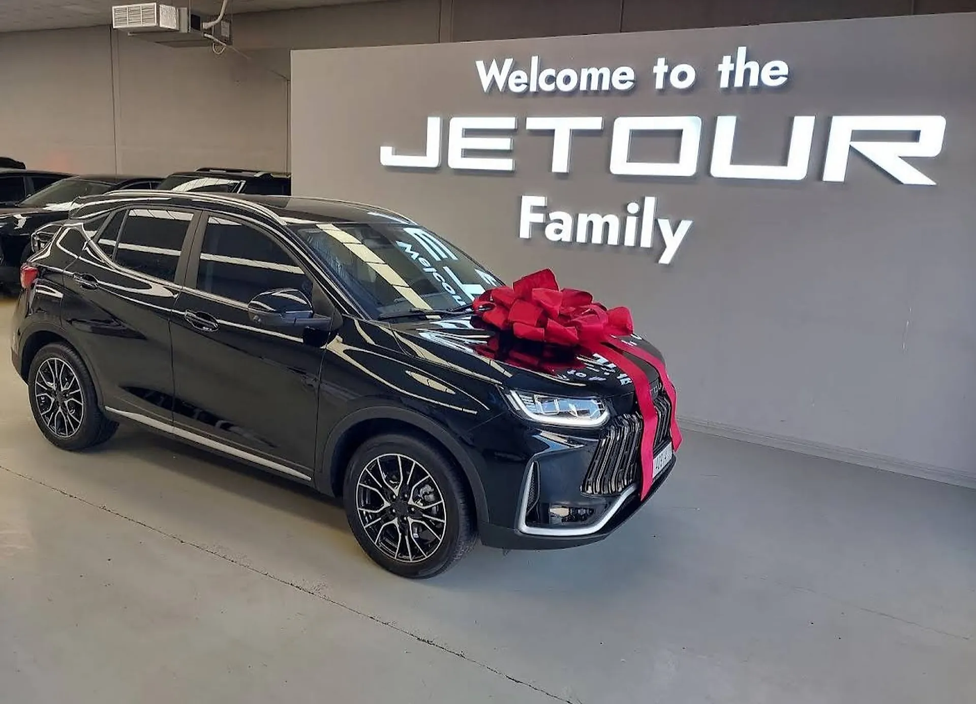 The handover area at the Jetour showroom in Dubai, a black SUV lit in front of a backlit welcome wall