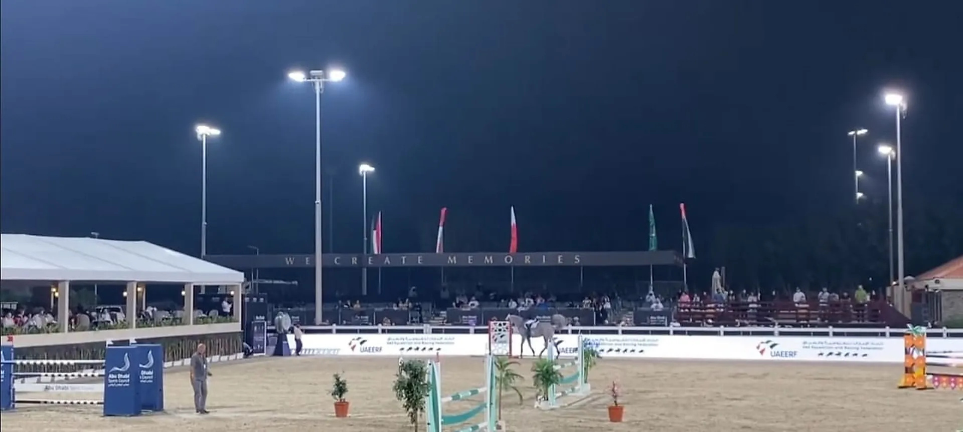 The outdoor competition arena at Mandara Equestrian Club at night, floodlit from masts around the perimeter
