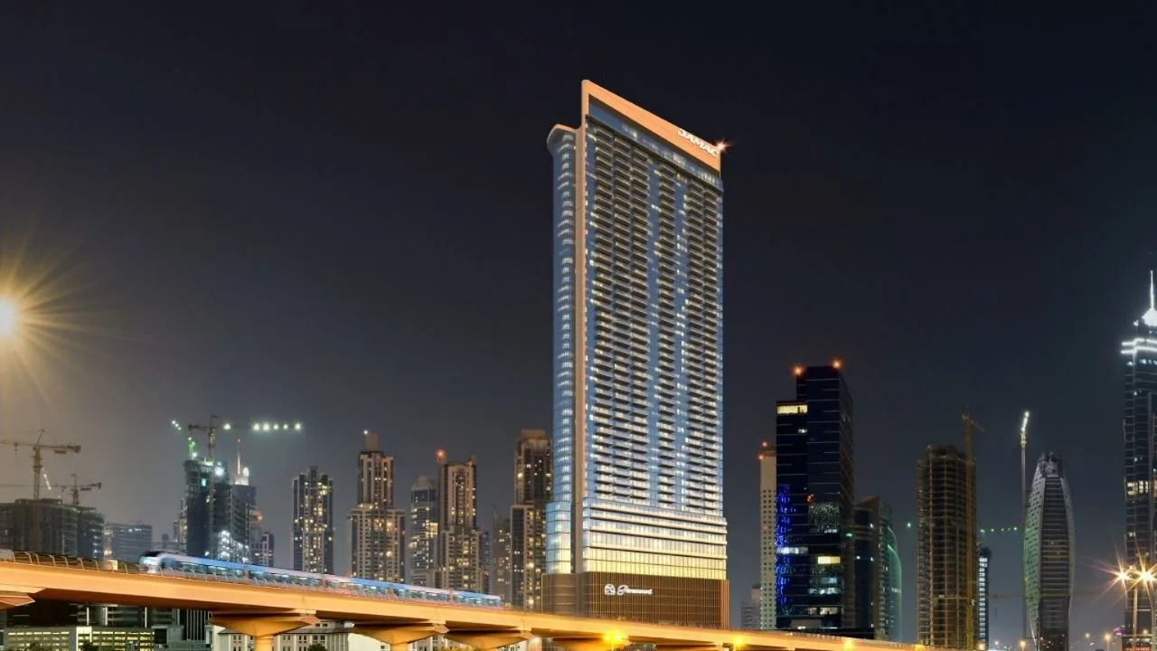 Paramount Tower at night seen across Business Bay, with a lit crown, a lit vertical corner and the metro viaduct in the foreground