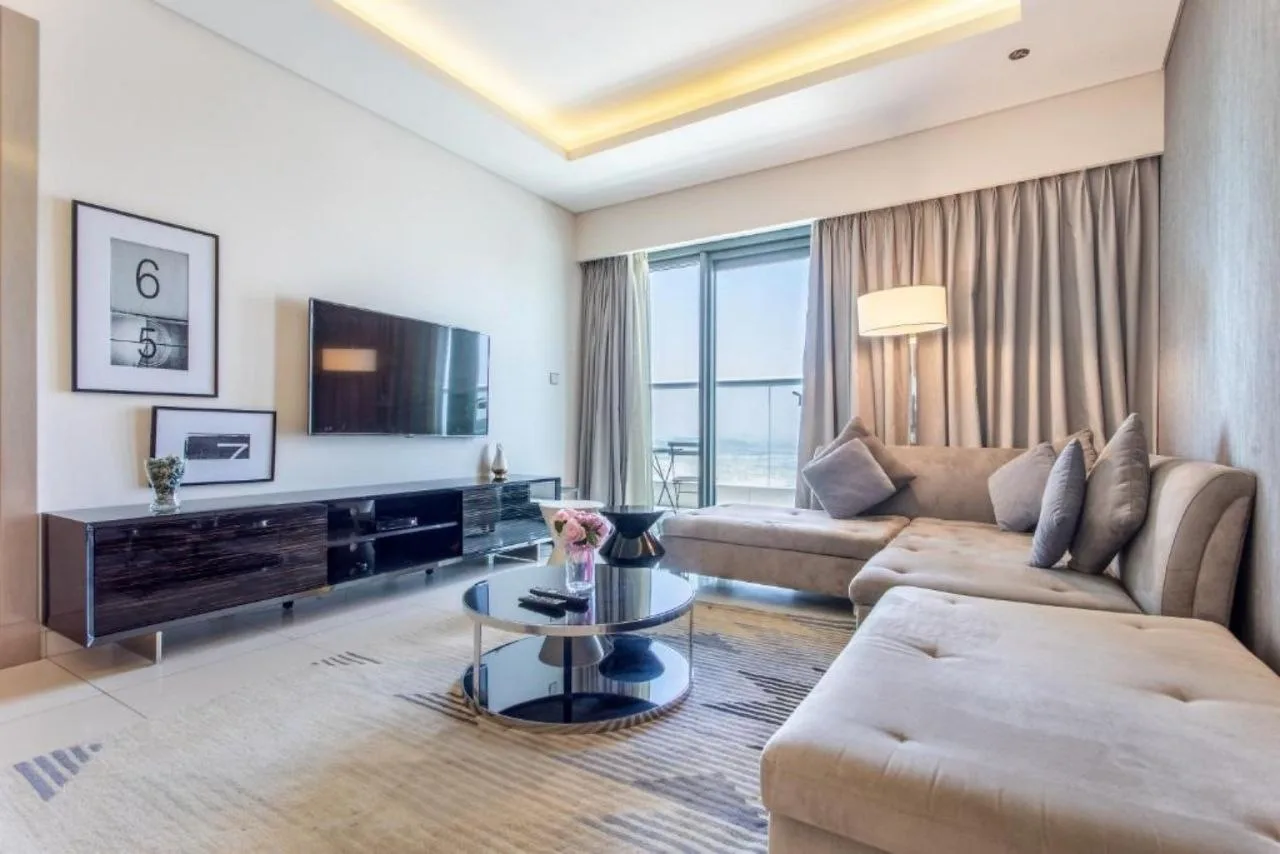 A serviced residence living room at Paramount Tower with a perimeter cove, a floor lamp and full-height glass to the balcony