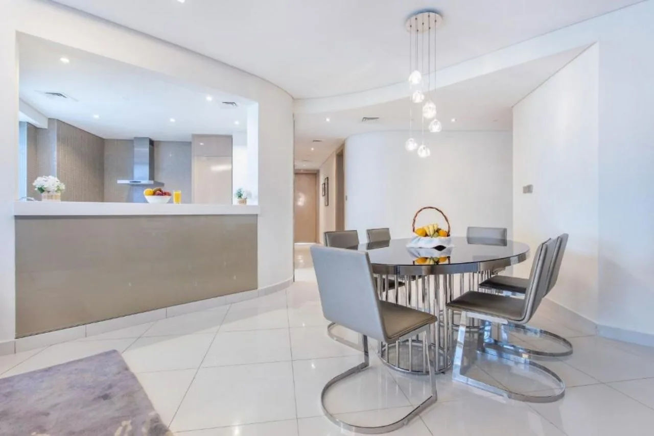 An open kitchen and dining area at Paramount Tower, lit by recessed downlights with a cluster of small pendants over the table