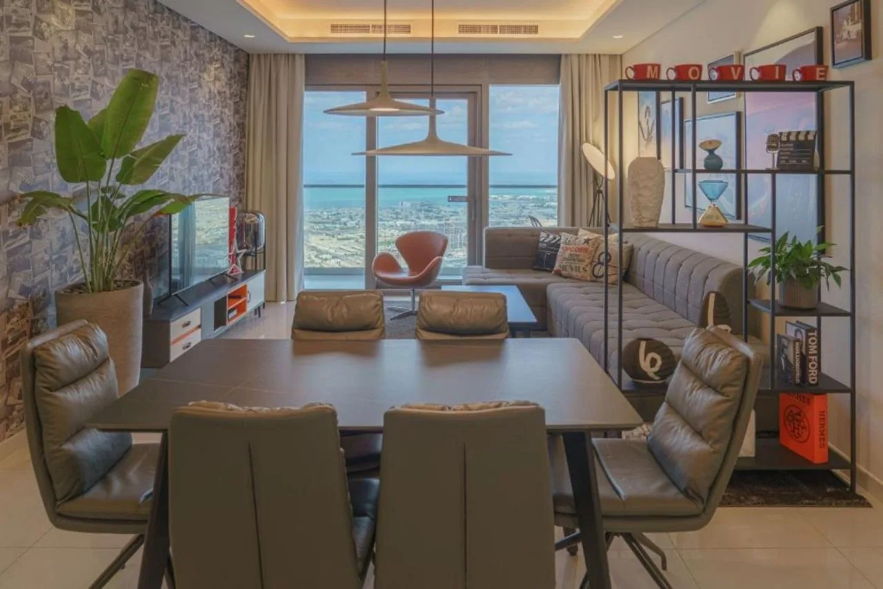 A residence at Paramount Tower with a dining table in the foreground and the living area and city view beyond