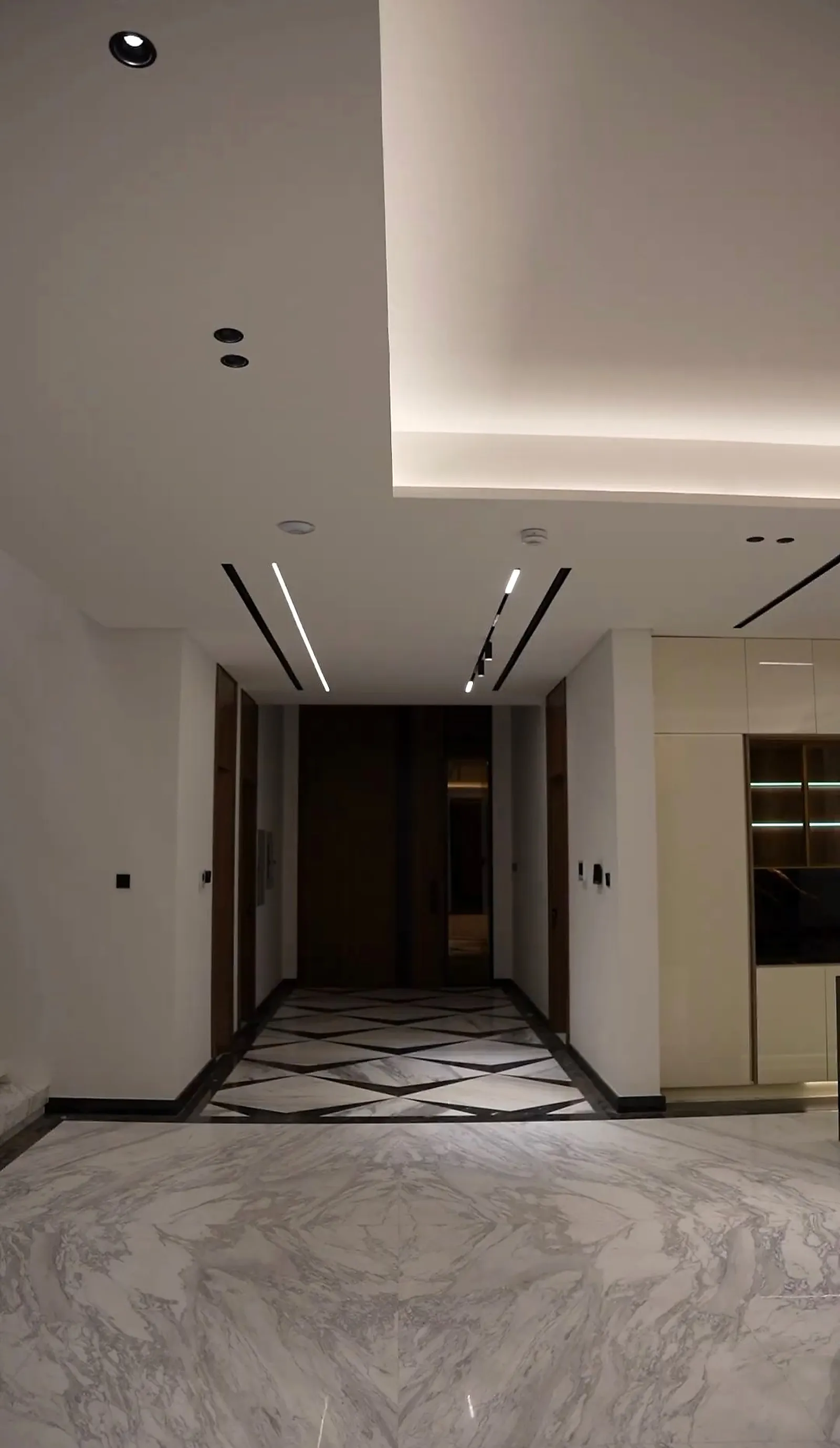 The ground-floor corridor, with a perimeter cove, a black recessed ceiling channel and patterned marble underfoot