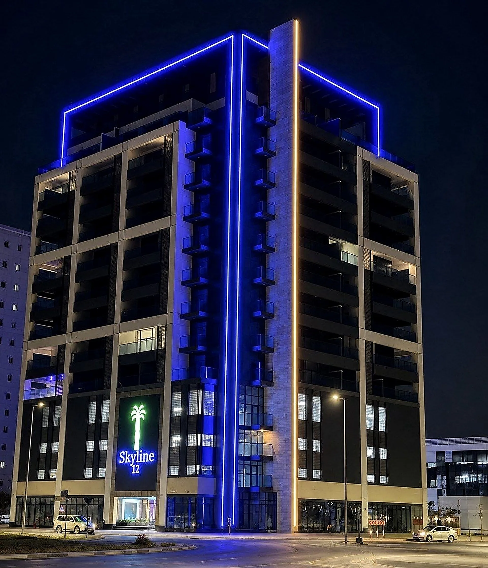 A mixed-use building in Dubai at night, its roof frame traced in blue linear light